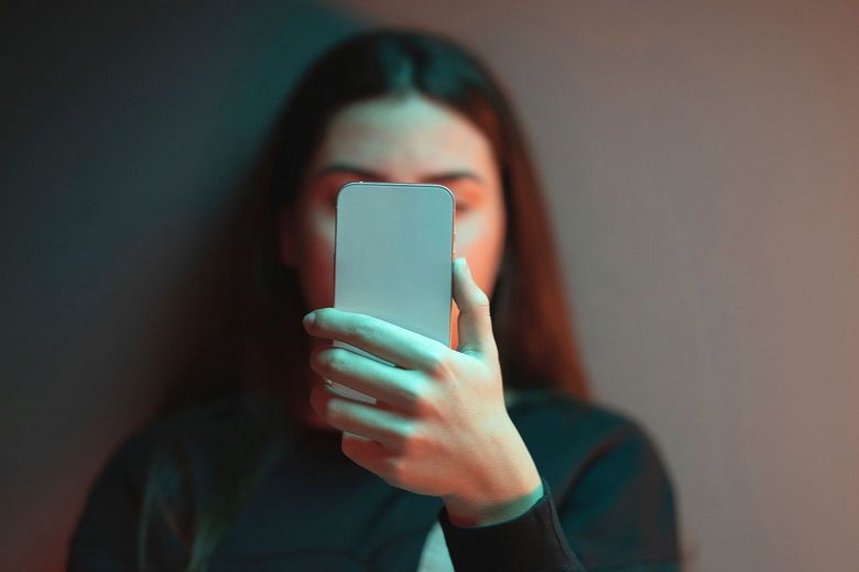 Junge Frau blickt auf ein Handy.