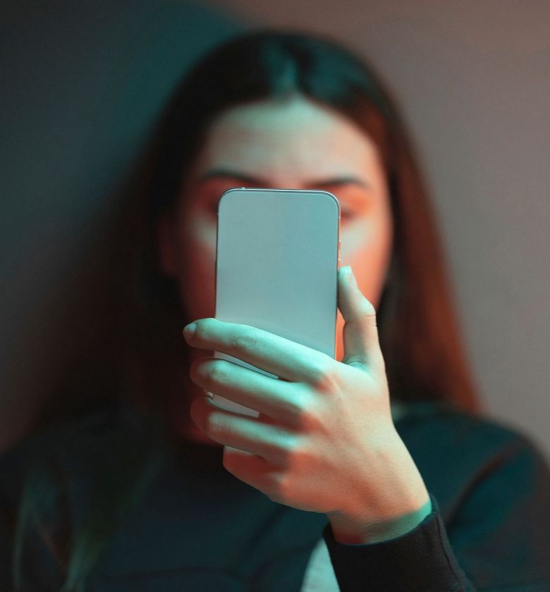 Junge Frau blickt auf ein Handy.