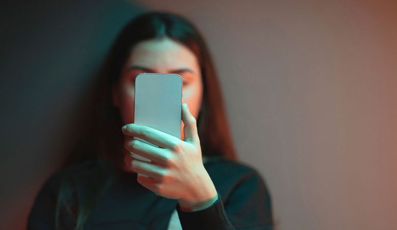 Junge Frau blickt auf ein Handy.