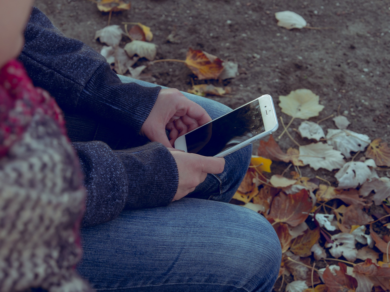Eine Nahaufnahme zeigt die Hände einer Person, die ein Smartphone halten.