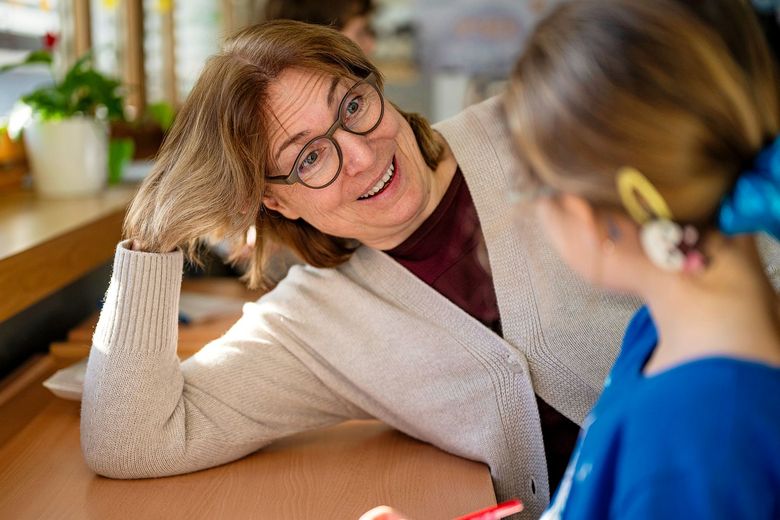 Eine Frau lehnt sich auf ein Pult und spricht mit einem Mädchen.