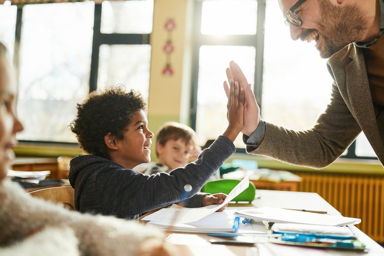 Lehrer gibt Schüler ein Highfive.