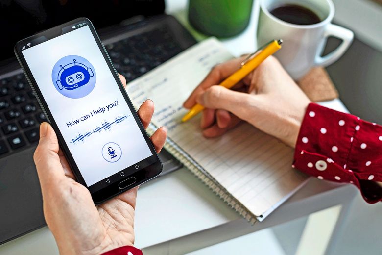 Eine Hand hält das Smartphone mit einem Chatbot, die andere Hand macht Notizen.