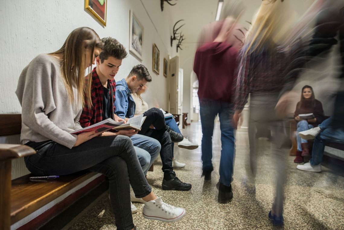 Jugendliche sitzen im Gewimmel des Schulhausflurs.