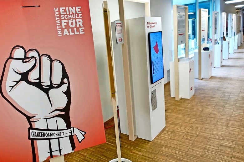 Ein Plakat mit einer in die Luft gestreckten Faust. Diese trägt an Armband, auf dem das Wort Chancengleichheit steht.