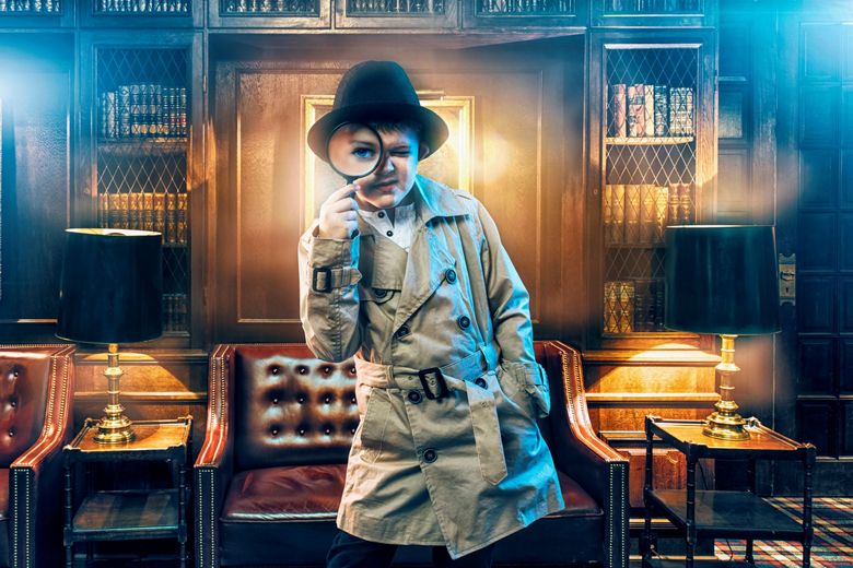 Ein Kind hält eine Lupe vor sein Gesicht. Es trägt einen Trenchcoat und einen Hut..