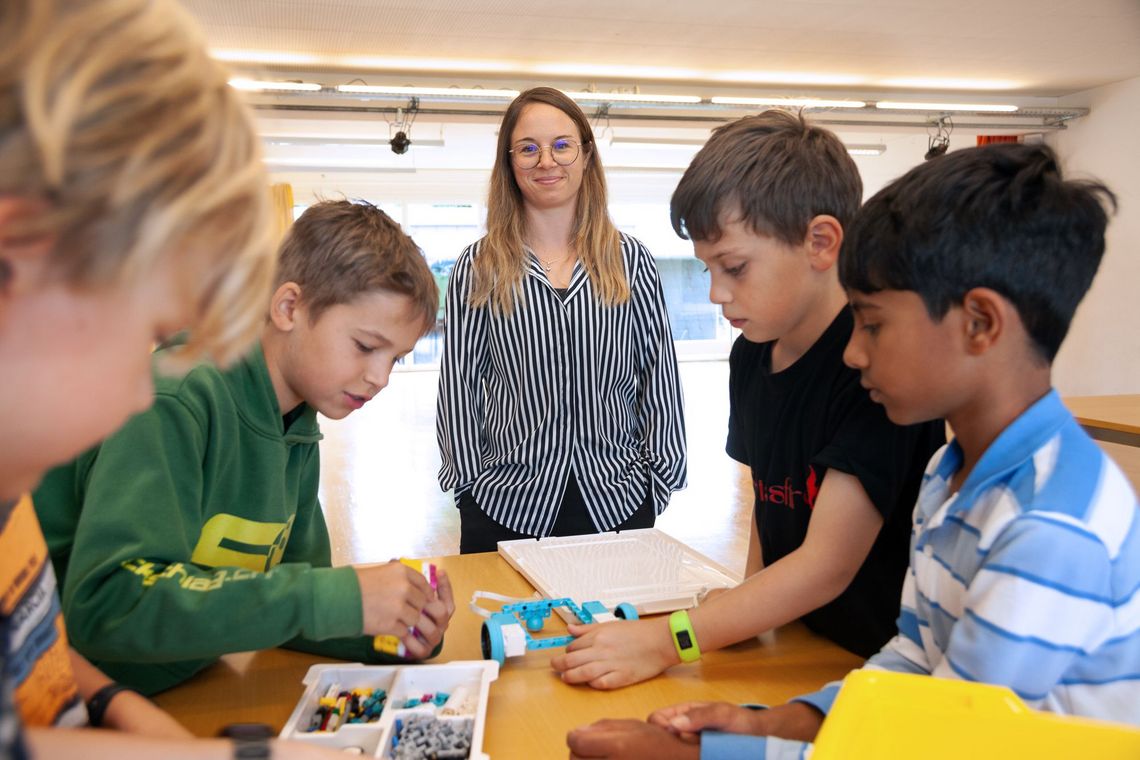 Eine Lehrerin sieht zu, wie Kinder Roboterteile zusammensetzen.