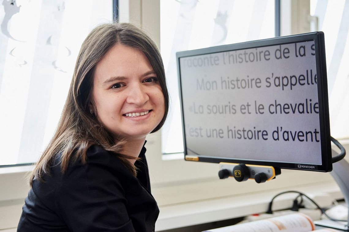 Michelle Bernasconi liest am Bildschirm einen Text mit sehr grosser Schrift.