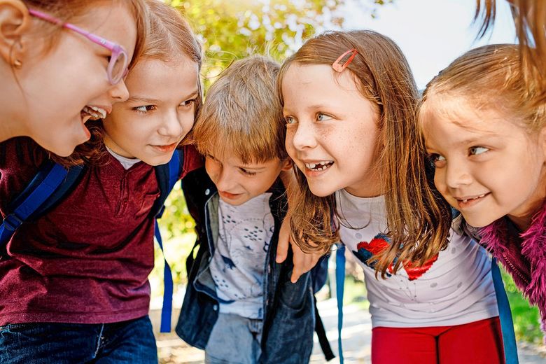 Eine Gruppe fröhlicher Kindern steckt verschwörerisch die Köpfe zusammen.