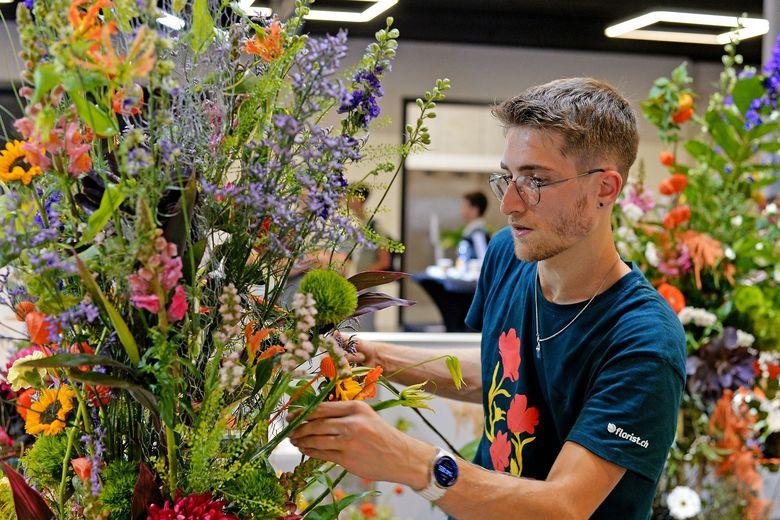 Ein Junger Mann arbeitet an einem Blumengesteck.