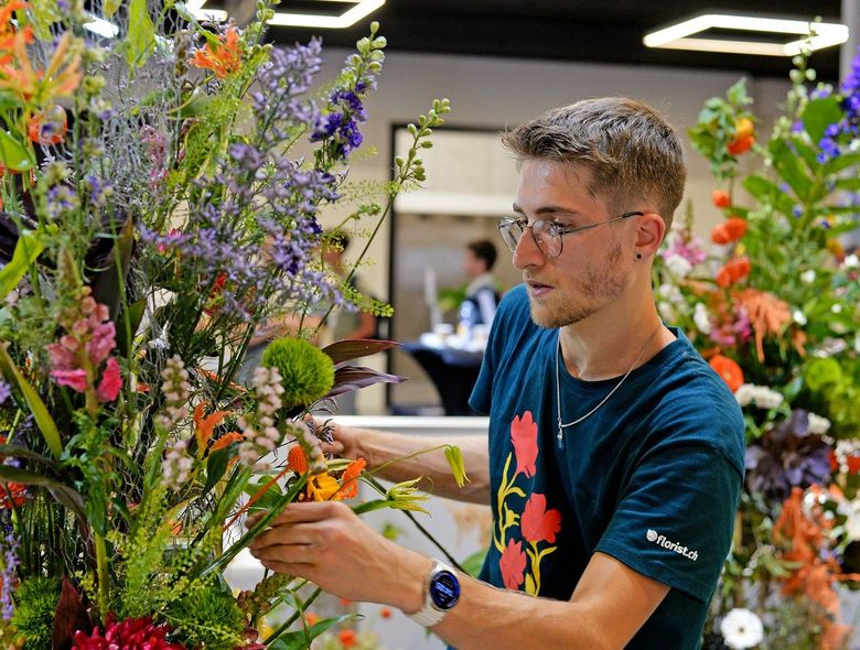 Ein Junger Mann arbeitet an einem Blumengesteck.