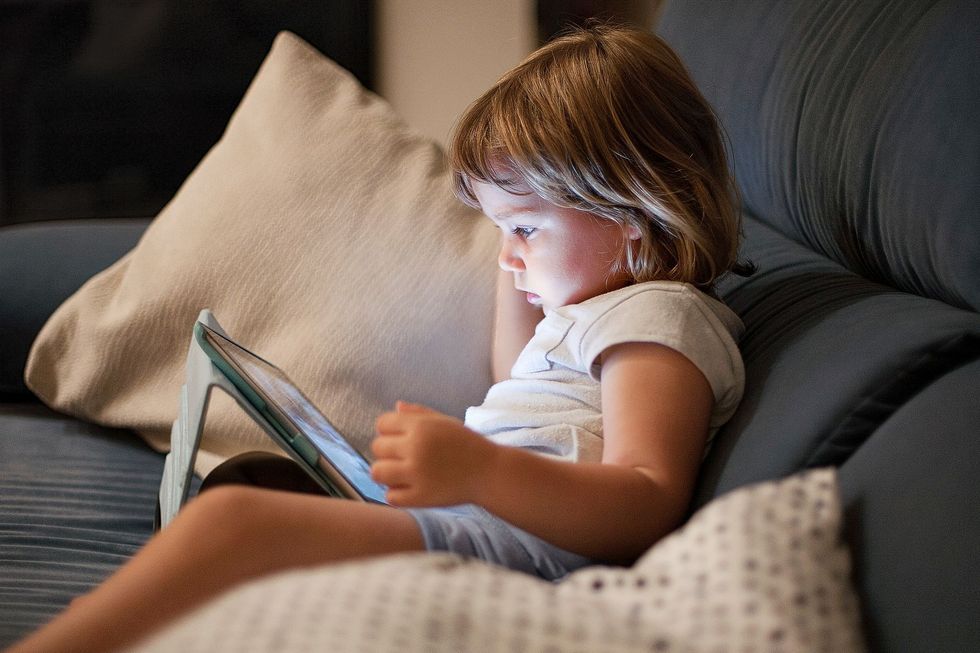 Bildschirmzeit Ein Tablet wirft kaltes Licht auf das Gesicht eine Kindes.