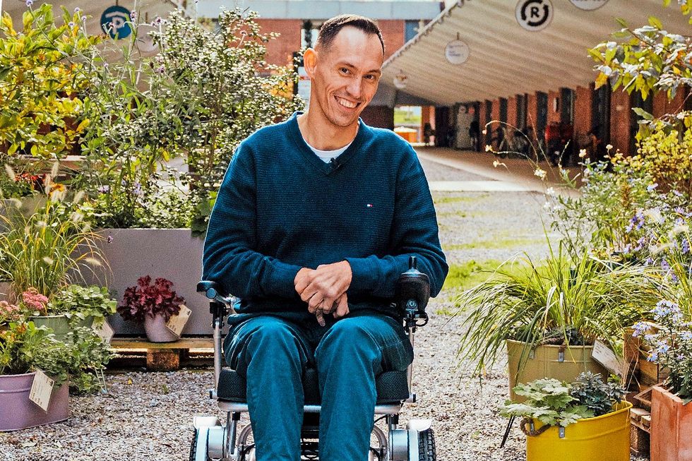 Islam Alijaj sitzt lächelnd im Rollstuhl.