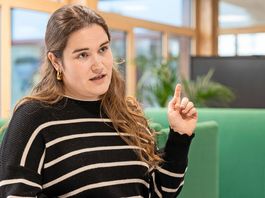 Eine Lehrerin in Nahaufnahme zeigt mit ihrem Zeigfinger hinter sich.