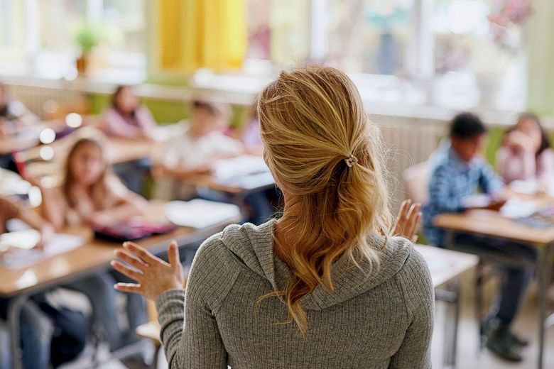Eine Lehrerin steht im Schulzimmer vor ihrer Klasse