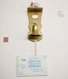 Ein Glocke mit einem Schwengel und einem motivierenden Spruch für Kinder, die lange krank waren.