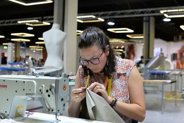Eine junge Frau sitzt konzentriert an der Nähmaschine.