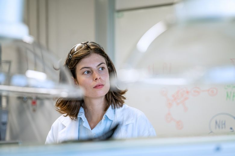 Eine Frau im Forscherinnnenkittel denkt nach.