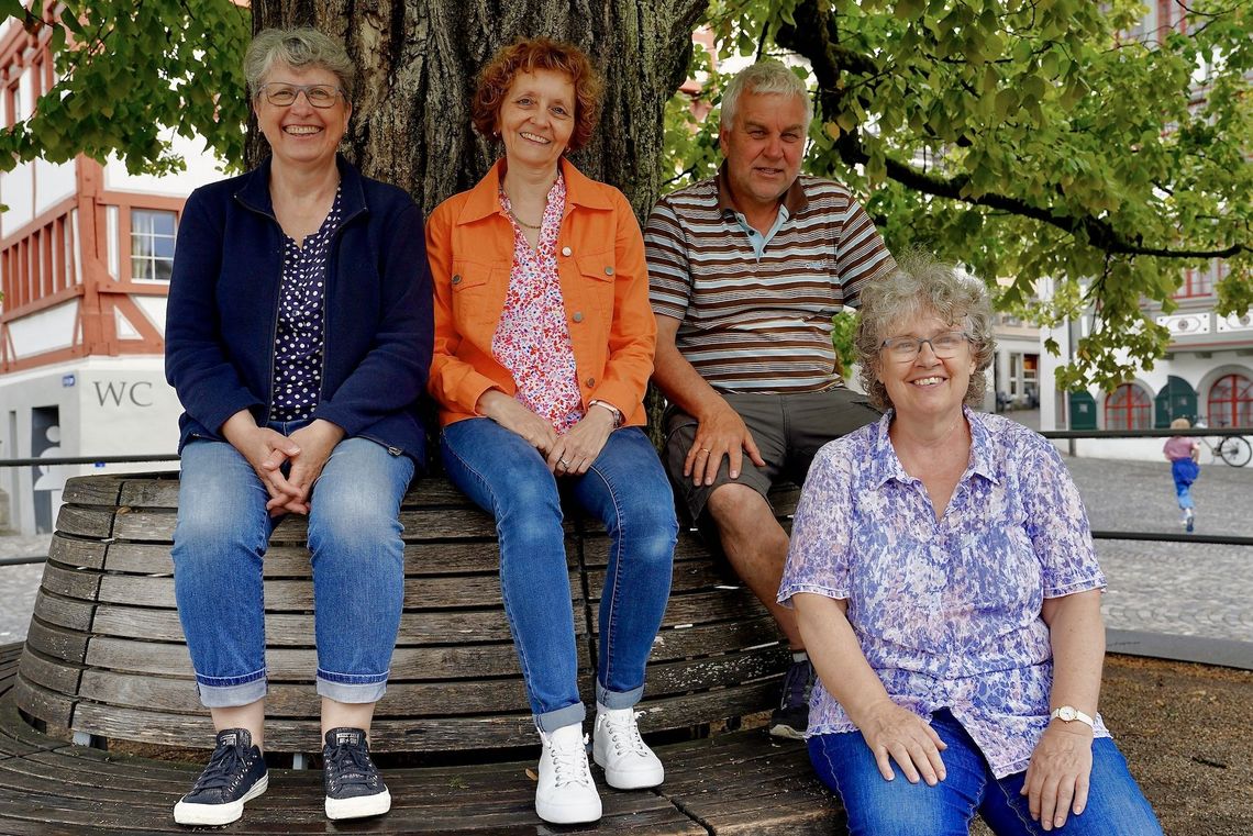 Helena Lüthi-Kunisch, Gabi Ammann, Reto Attenhofer und Irene Höltschi sitzen auf einer Bank vor einem Baum.