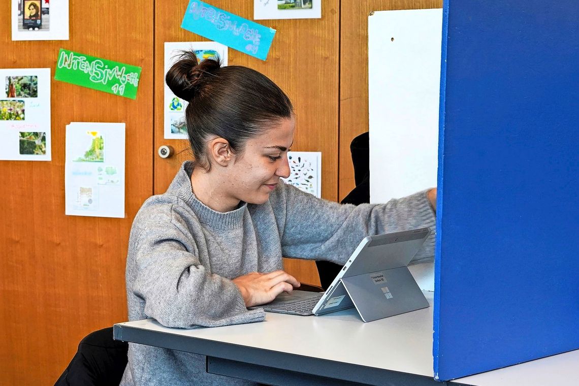 Schülerin vor blauer Trennwand.