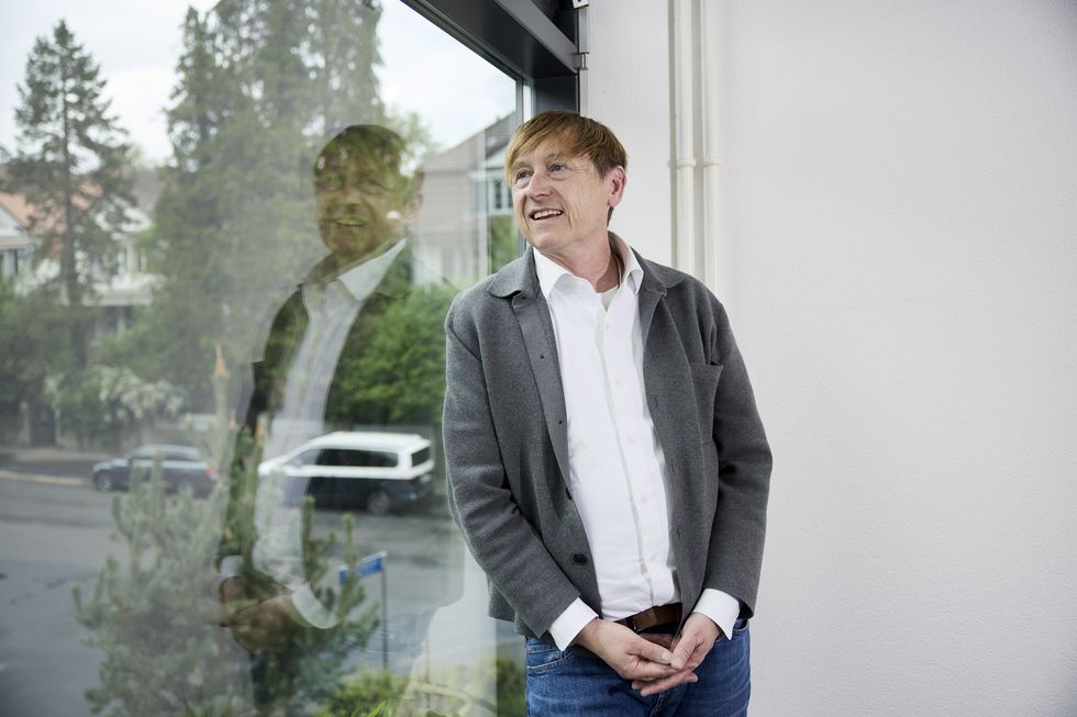 Preisüberwacher Stefan Meierhans lehnt an einem Fenster und schaut nach draussen.