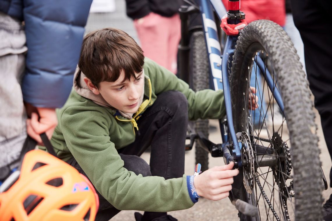 Ein Knabe befestigt ein Rad des auf den Sattel gedrehten Mountain Bikes.