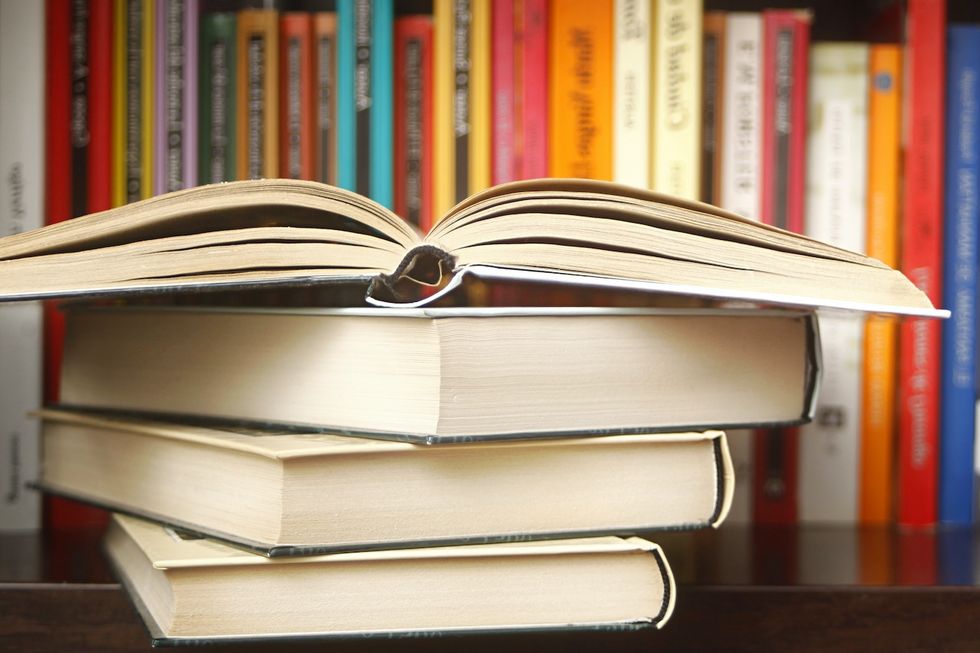 Ein aufgeschlagenes Buch liegt auf einem Bücherstapel im Buchregal.