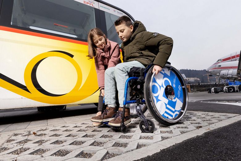 Schulkind im Rollstuhl begleitet von einem Mädchen.