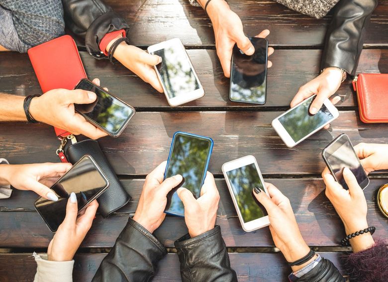 Blick auf einen Tisch voller Smartphones.