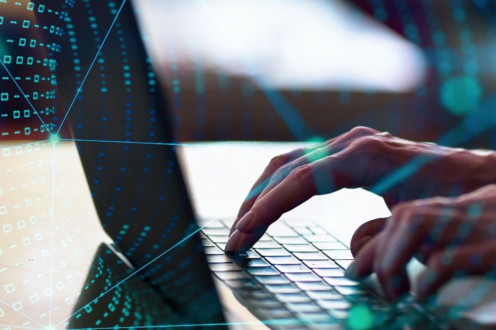 Hände tippen auf einem Laptop umgeben von einem virtuellen Netzwerk.