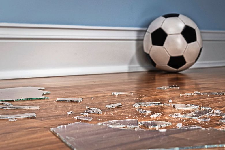 Ein Holzboden, übersät mit Glasscherben, daneben ein Fussball. Foto: iStock/cmannphoto