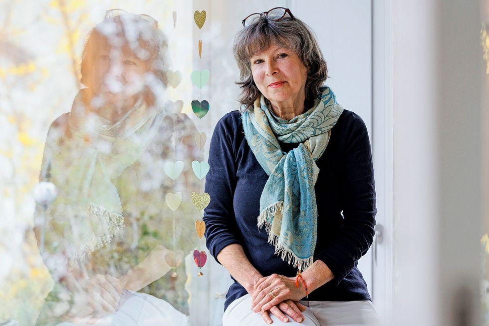 Eine Frau sitzt auf dem Sims eines Fensters.