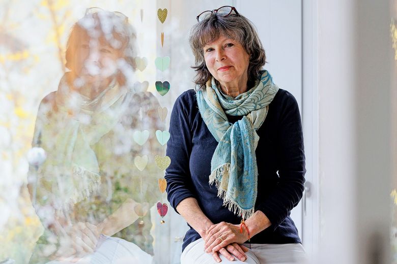 Eine Frau sitzt auf dem Sims eines Fensters.