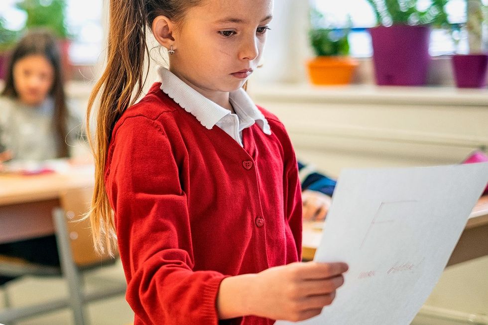 1144644336 Ein Mädchen schaut mit gesenkten Augen auf ihr Notenblatt.