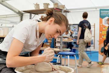 Eine junge Frau arbeitet an der Töpferscheibe.