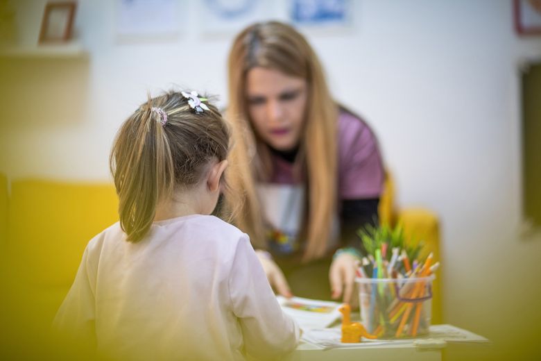 The educator works with a small child in a children's workshop Lehrerin leitet Schulkind beim Erledigen einer Aufgabe an