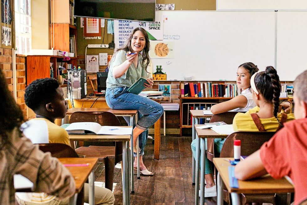 Eine Lehrperson spricht vor einer Klasse.