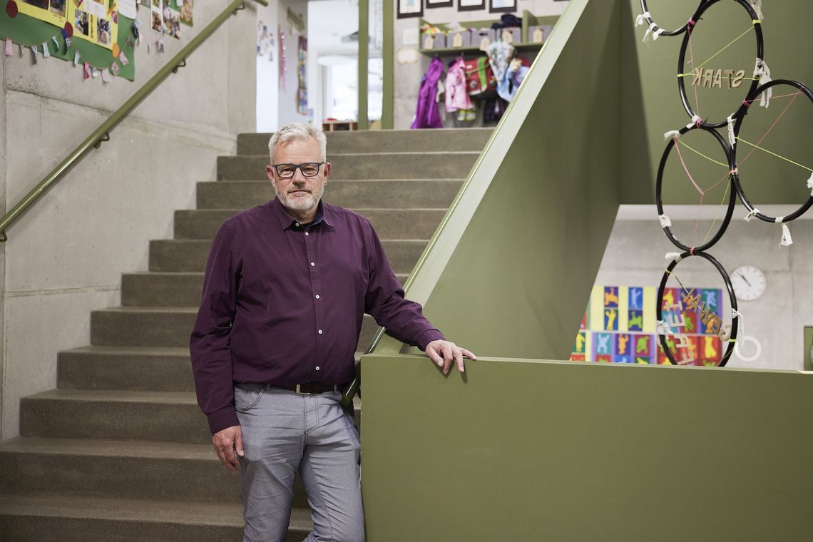 Schulleiter Jürg Kaufmann steht auf einer Treppe in der Schule.