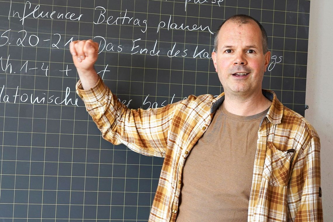 Lehrer zeigt auf eine Wandtafel.