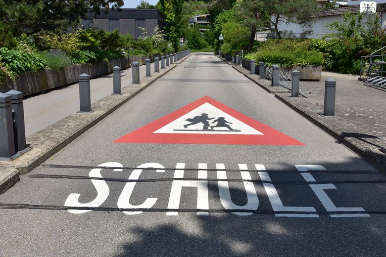 Strassenmarkierung auf Schulweg mahnt Autos, vorsichtig zu fahren.
