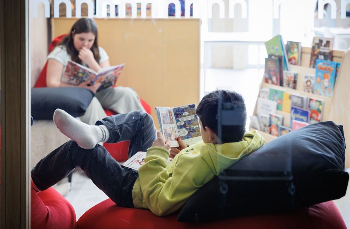 Reportage Tagesschule Prêles Kinder sitzen zusammen und spielen mit bunten Schnüren.