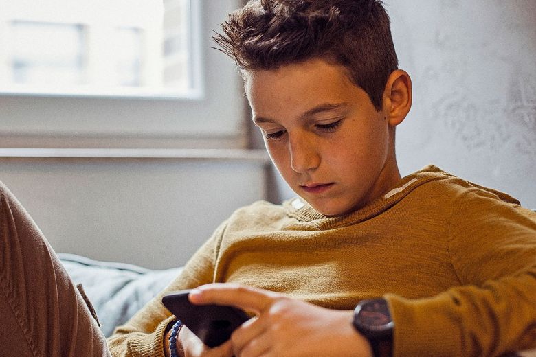 1165490497 Ein Junge blickt in sein Handy.