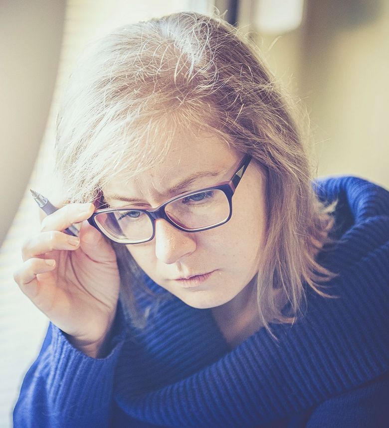 Erwachsene Frau greift sich beim Lesen an die Brille.