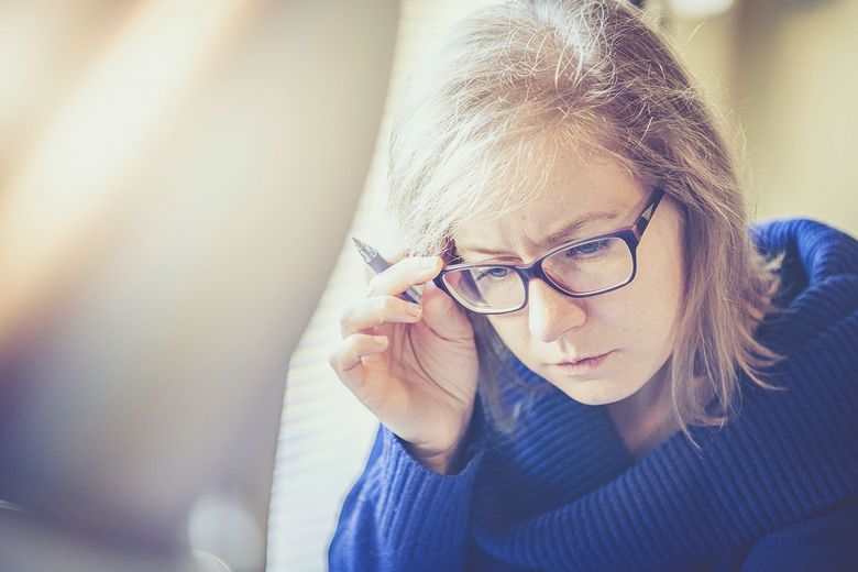 Erwachsene Frau greift sich beim Lesen an die Brille.