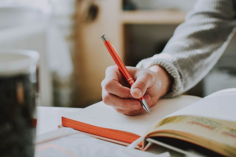 Eine Person schreibt mit einem Stift in ein Buch.