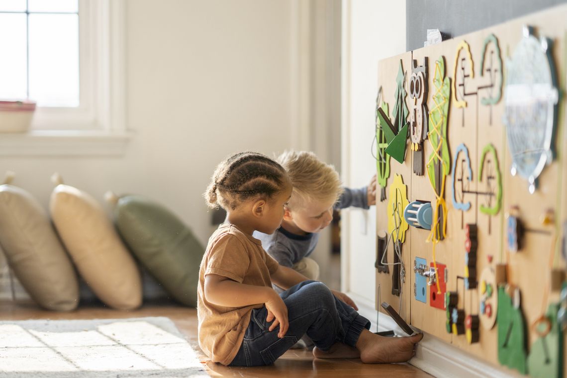 Ein Mädchen und ein Junge im Einschulungsalter spielen gemeinsam an einer bunten Wand.