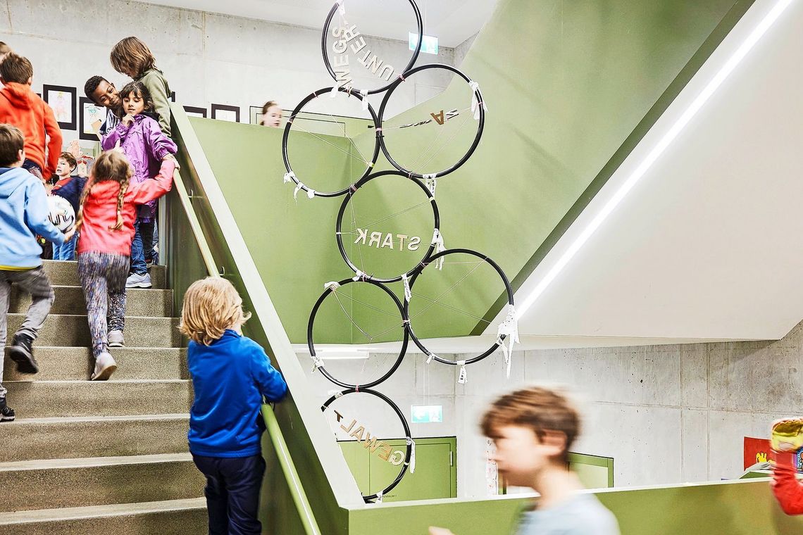 Kinder gehen im Treppenhaus eine Treppe hinauf.