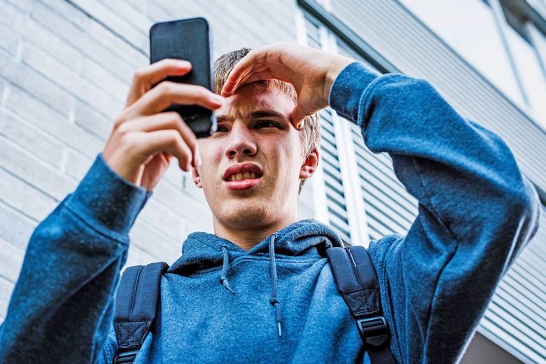Teenager schaut verstört in sein Smartphone.