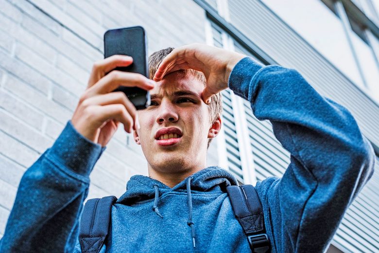 Teenager schaut verstört in sein Smartphone.
