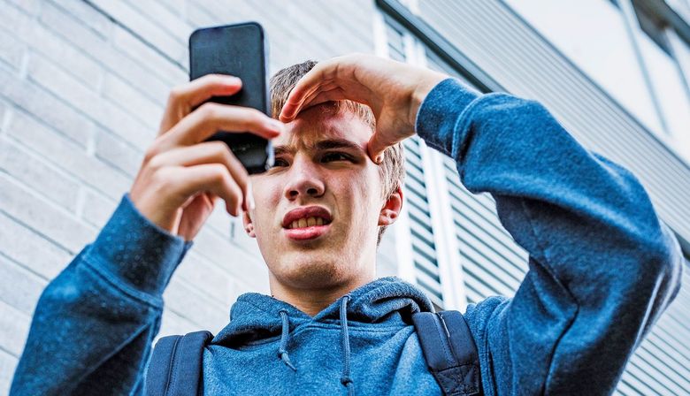 Teenager schaut verstört in sein Smartphone.